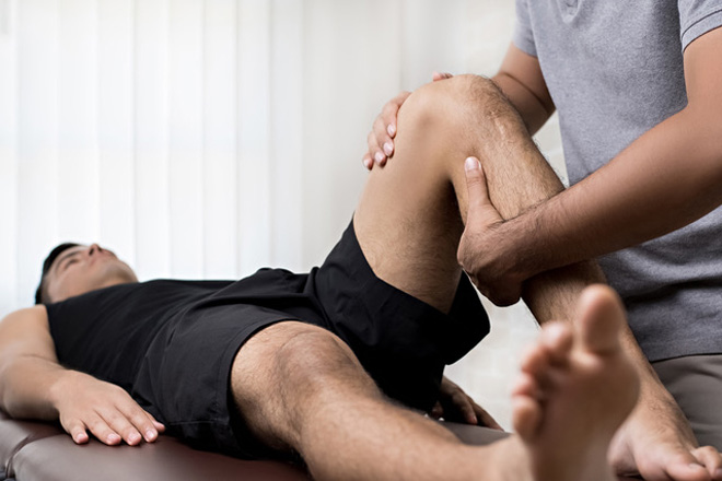 Oellerich Physiotherapie: Therapeut behandelt das Bein eines Mannes